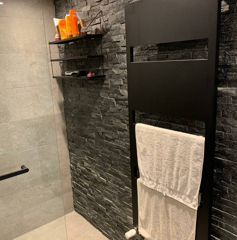 Badkamer met zwarte radiator en steenstructuur